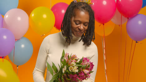 Studioporträt-Einer-Frau-Mit-Geburtstagsstirnband,-Die-Einen-Blumenstrauß-Hält-Und-Mit-Luftballons-Feiert-1